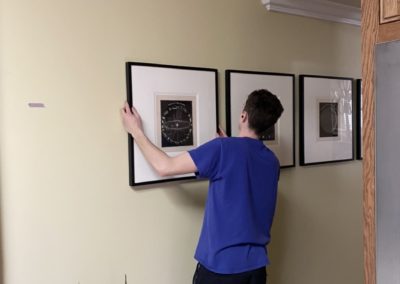 Assistant hanging photos in Venice home