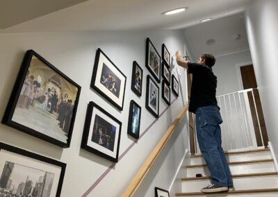 Assistant working on gallery wall in stairwell